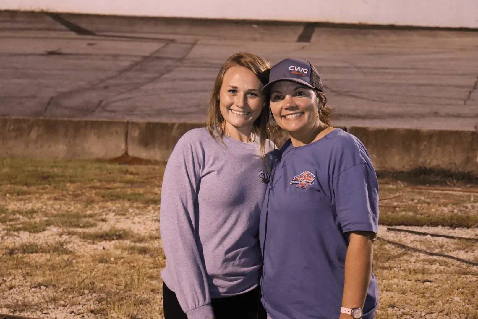 Two women standing next to each other in a field.