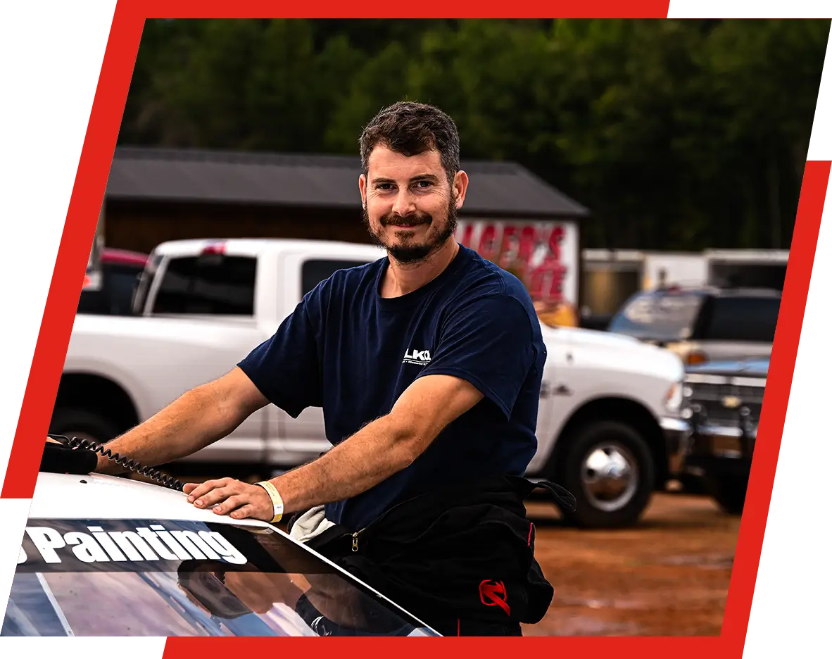 A man standing next to a truck in the parking lot.