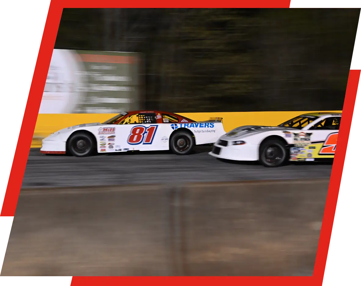 Two cars are racing on a track at night.