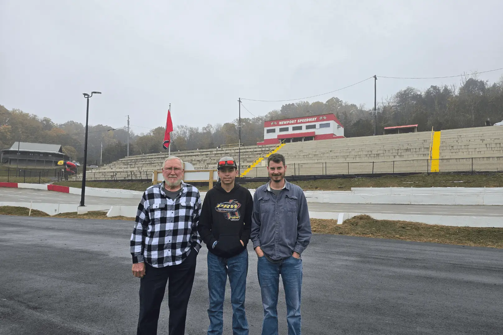 Three men standing at a race track.