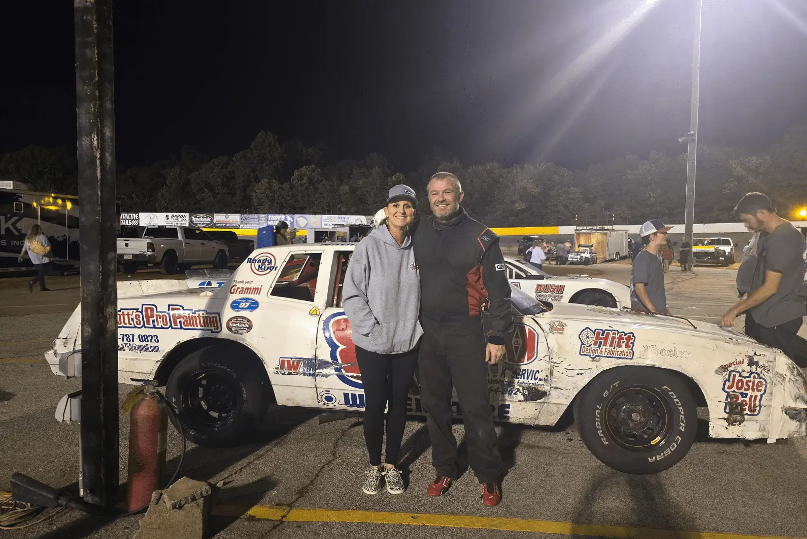 A man and woman standing in front of a race car.